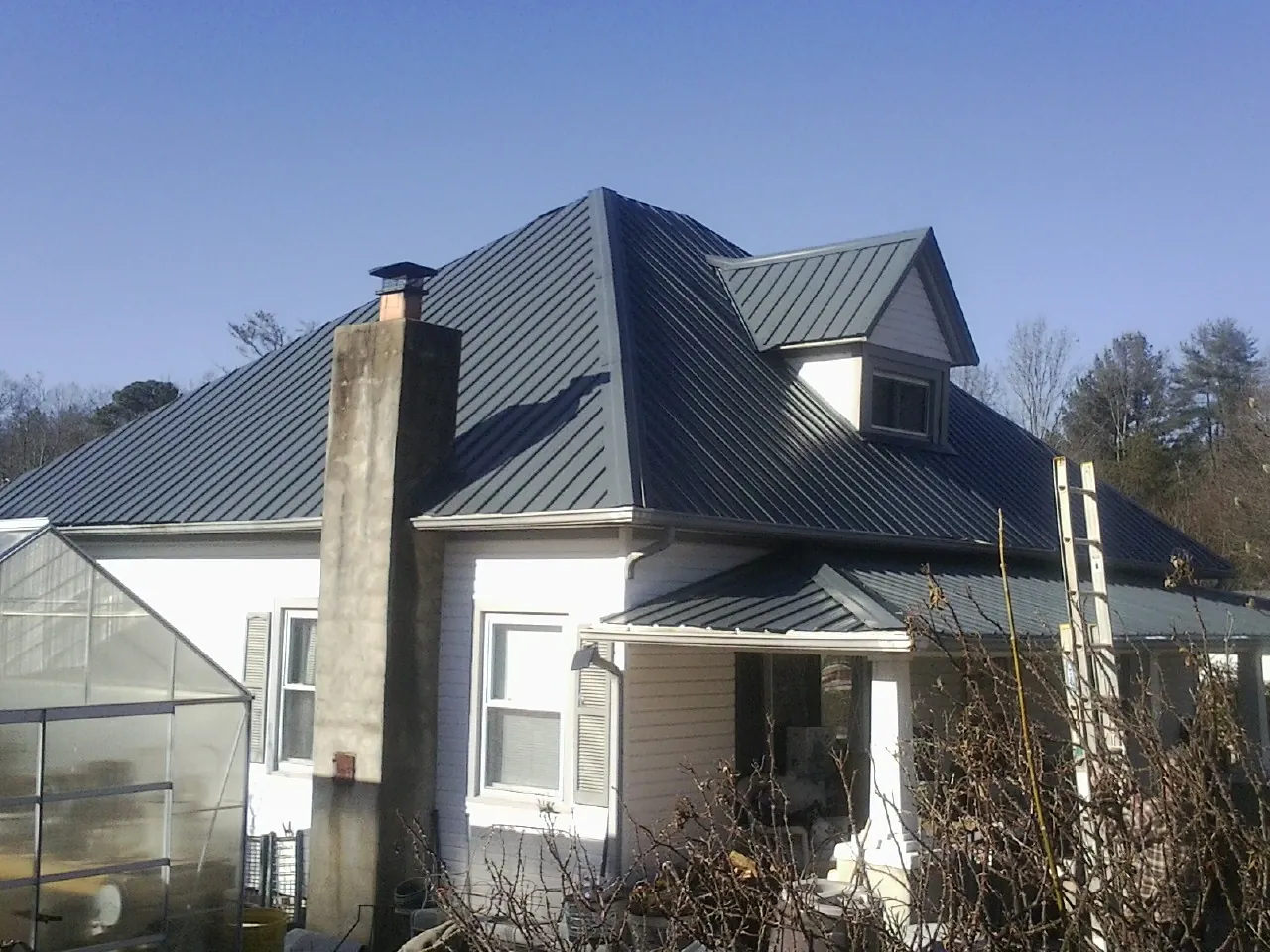 Dark blue standing seam metal roof on a white farmhouse with dormer — Slate & Tile Roof Repair by Roofing Brothers in Lackawaxen