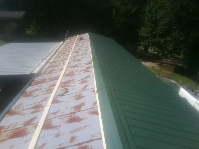 Old rusted panels beside newly installed green metal roofing — Wind Damage Roof Repair by Roofing Brothers in Lackawaxen