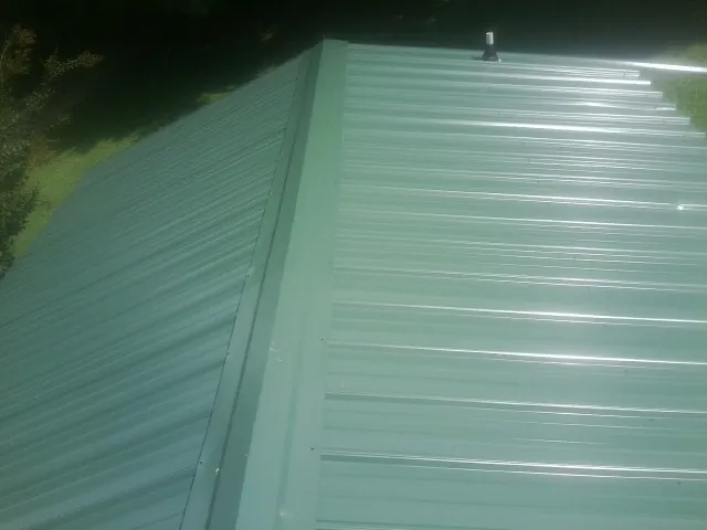 New green metal panels meeting at the ridge of a roof — Flat Roof Repair work by our crew in Lackawaxen