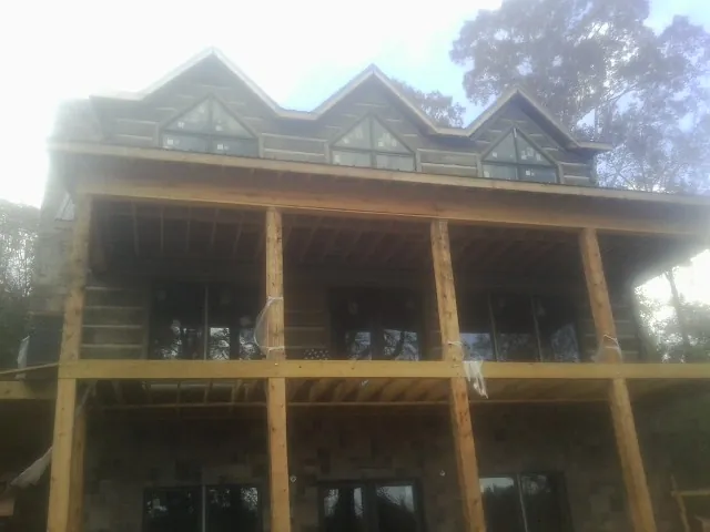 Dormers and porch framing on a large log home under construction — Roof Coating work by our crew in Lackawaxen