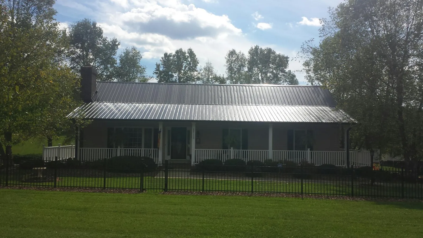 Gray metal roof on a brick ranch with a full width front porch — Gutter Guard Installation work by our crew in Lackawaxen