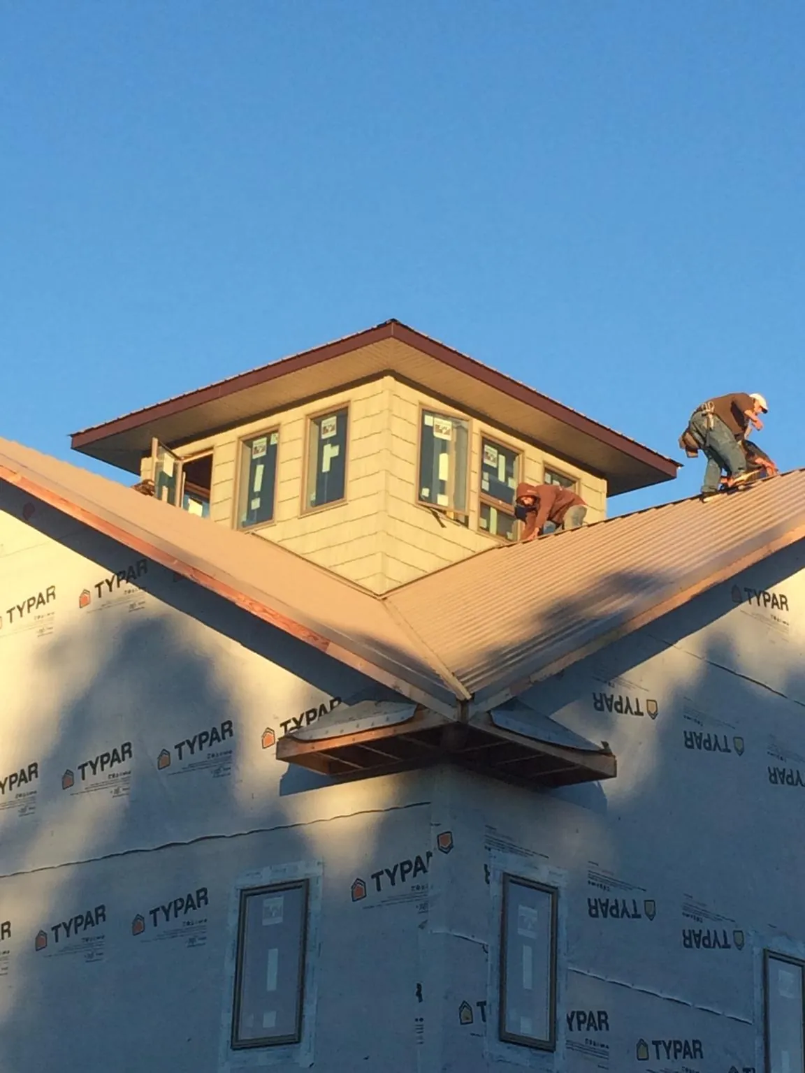 Roofers working around a rooftop cupola on a new metal roof at sunset — Roof Waterproofing in Lackawaxen by Roofing Brothers